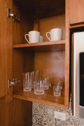 a set of glasses on a shelf in a kitchen at Santa Delfina Suites in Flores