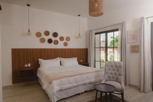 a bedroom with a bed and a chair and a window at Santa Delfina Suites in Flores