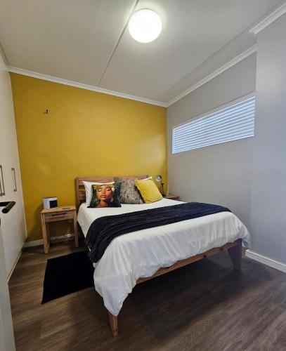 a bedroom with a bed and a yellow wall at R&R at Summerview Sonstraal Heights in Windsor Park