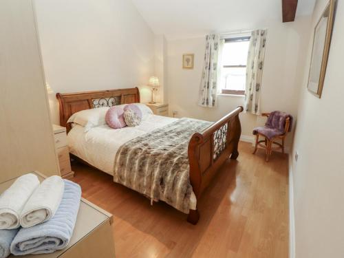 a bedroom with a bed and a chair and a window at Millers Cottage in Wigton
