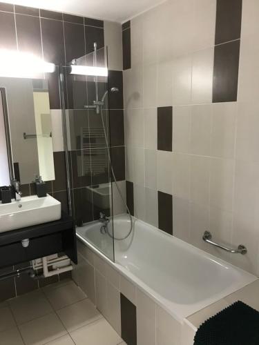 a bathroom with a tub and a sink and a shower at Appartement village 7 in Arles