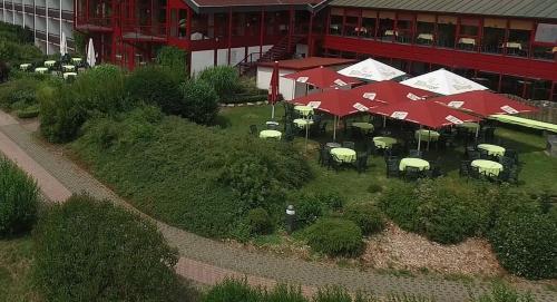 a bunch of tables with umbrellas in front of a building at Hessen Hotelpark Hohenroda in Hohenroda