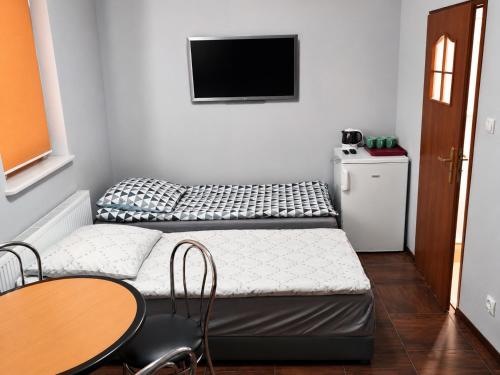 a room with two beds and a table and a tv at Domek STABOL in Kołobrzeg