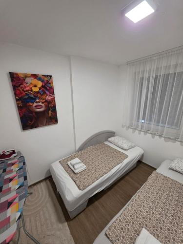 a bedroom with two beds and a painting on the wall at Apartman IVA in Modriča