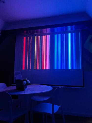 a room with a table and a screen with colorful bars at Le Nuage - Vidéoprojecteur - Terrasse - 5min Gare in Ploumagoar