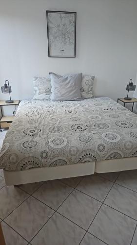 a large bed in a bedroom with a white wall at Les Gites D'Angres in Angres
