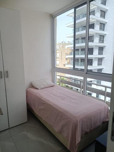 a bedroom with a bed and a large window at Dizengoff 20 in Netanya