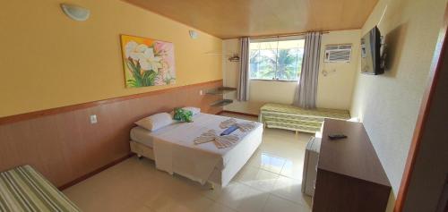 a small room with a bed and a window at Pousada Duas Praias in Guarapari