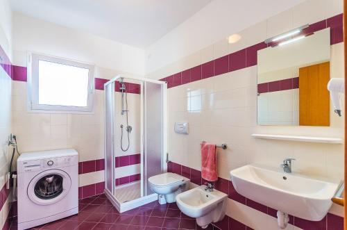 een badkamer met wastafel en wasmachine bij Residence Ca'Tullio in Bibione