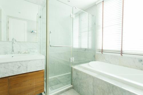 a bathroom with a shower and a tub and a sink at Thomson Residence Hotel in Bangkok
