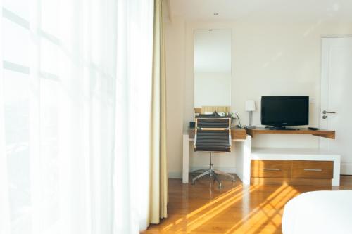 a bedroom with a desk with a computer and a television at Thomson Residence Hotel in Bangkok