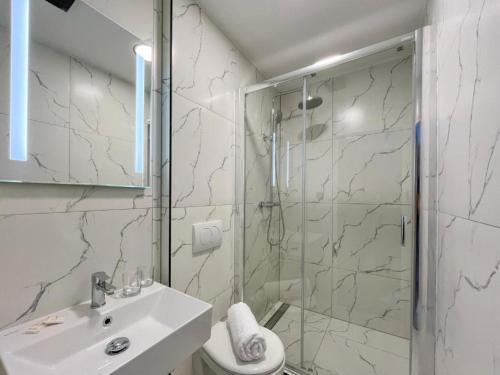 a white bathroom with a shower and a sink at RS Hotel in Rimavská Sobota