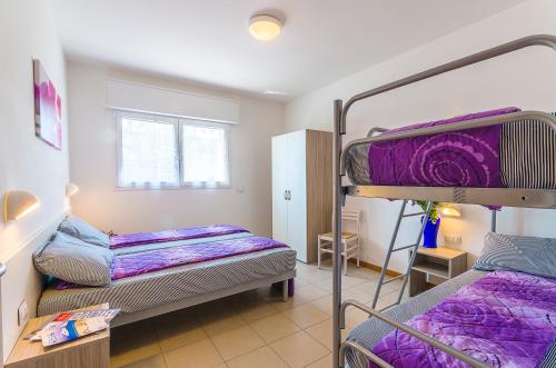 ビビオーネにあるResidence Ca'Tullioの紫のシーツが備わる客室の二段ベッド2台