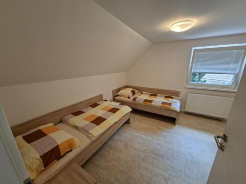 two beds in a small room with a window at Zavetišče v Gozdu in Križe