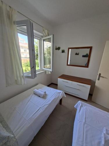 a white bedroom with a bed and a window at Apartments Marino in Supetar
