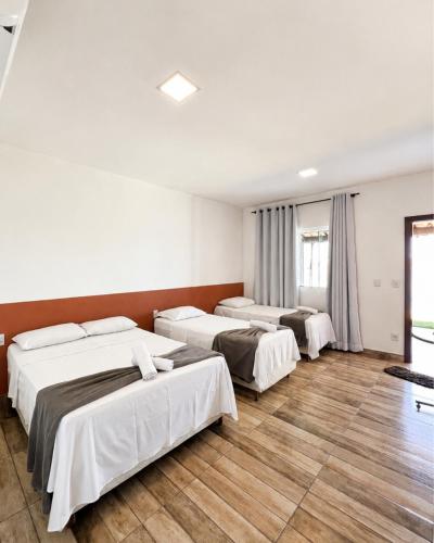 three beds in a room with wooden floors at Brisa do Lago Pousada in Capitólio