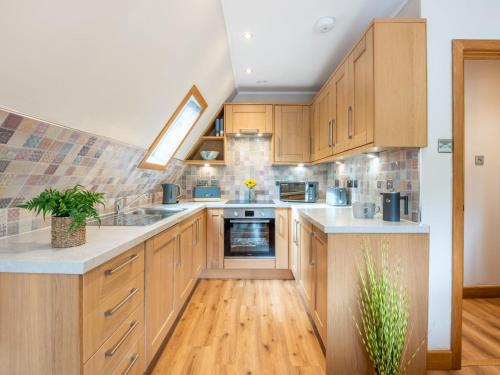 a kitchen with wooden cabinets and white counter tops at Chalet Glengarry Combi by Interhome in Spean Bridge