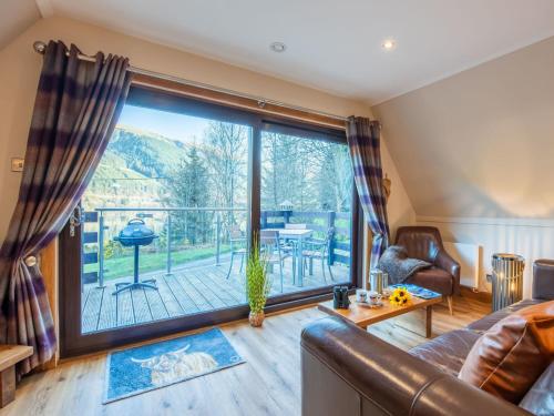 a living room with a large window with a view of a deck at Chalet Glengarry Combi by Interhome in Spean Bridge