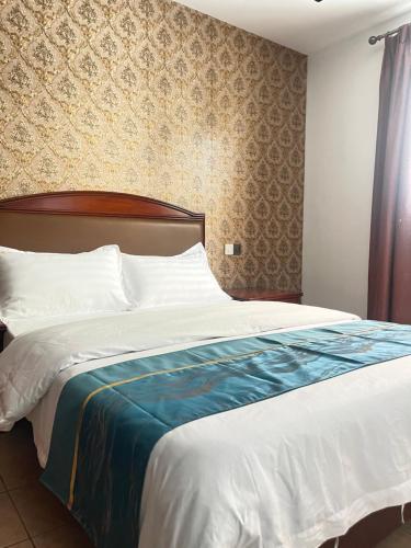 a bedroom with a large bed with white sheets at HH Inn in Lagos