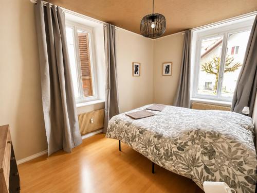 a bedroom with a bed and two windows at vaste appartement rénové avec terrasse in Morteau