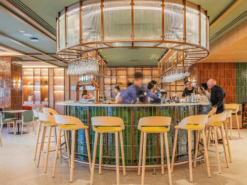 a restaurant with a bar with yellow bar stools at Novotel Lisboa in Lisbon
