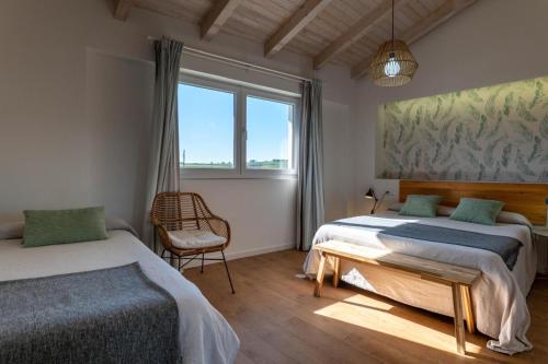 a bedroom with two beds and a chair and a window at La Casita de Melón in Suances