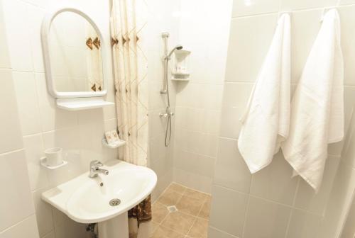 y baño blanco con lavabo y ducha. en Lovech Sport, en Riazán