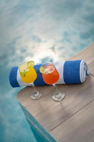 two wine glasses sitting on a table next to a pool at EOS Suites in Santa Cruz Huatulco