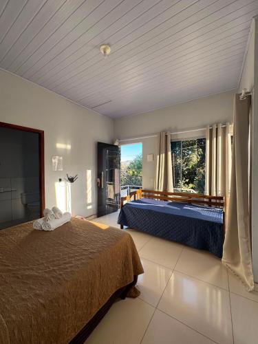 a bedroom with two beds and a large window at Chalés Aconchego in Cavalcante