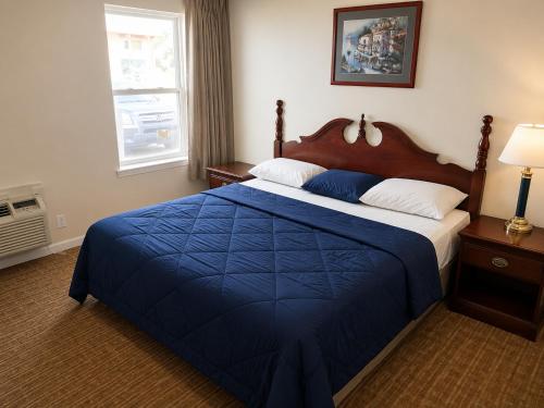 a bedroom with a bed with a blue blanket and a window at Tumbleweed Inn & Suites in Alexander