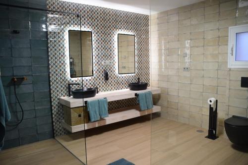 a bathroom with two sinks and two mirrors at Cortijo el Viznagar in Las Casicas