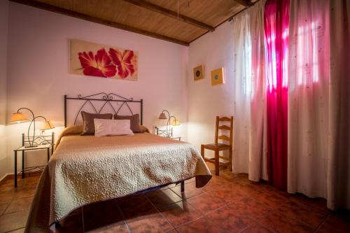 um quarto com uma cama num quarto com cortinas vermelhas em Casa Rural Espinarural em Almogía