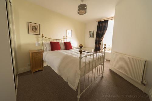 um quarto com uma cama com almofadas vermelhas e uma janela em Belle Vue Terrace Apartment em Great Malvern