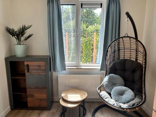 a swing chair in a room with a window at Vida Bonita in Den Burg