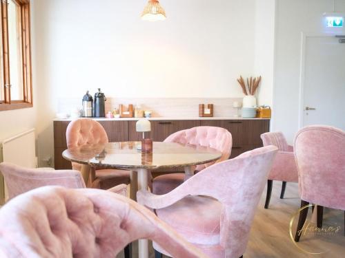 a dining room with pink chairs and a table at Seaside Stay Haverdal in Haverdal