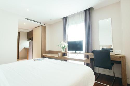 a bedroom with a bed and a desk and a television at Thomson Residence Hotel in Bangkok