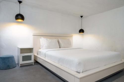 a white bedroom with a white bed and two lights at Elokut in San Juan