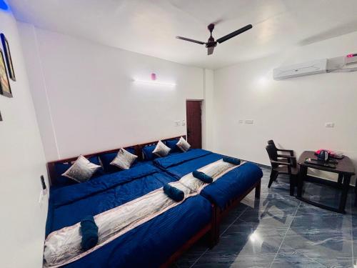 a large blue bed in a room with a table at The Loop - Auroville Main Junction, 5-Minute Drive to Auroville Beach & ECR Road, High-Speed WiFi & Free Parking in Pondicherry