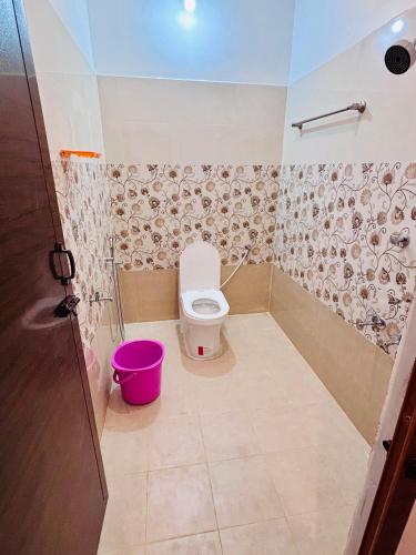 a bathroom with a toilet and a pink bucket at The Loop - Auroville Main Junction, 5-Minute Drive to Auroville Beach & ECR Road, High-Speed WiFi & Free Parking in Pondicherry