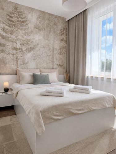 a white bedroom with a large bed with a window at Apartament Premium Orzysz in Orzysz