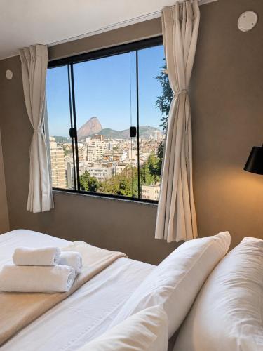 a bedroom with a bed and a large window at New Sugar Loft Apartments in Rio de Janeiro