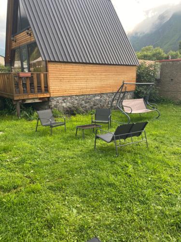 a group of chairs in the grass in front of a building at Sunny Side Cottage in Kazbegi