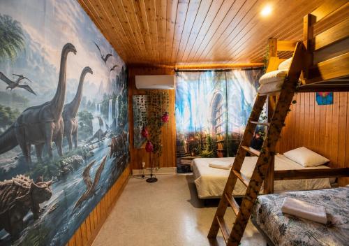 a bedroom with a mural of dinosaurs on the wall at Ciné Lodge Lourdes in Lourdes