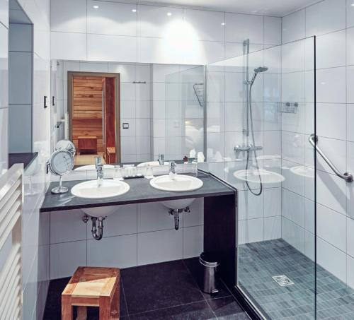 a bathroom with two sinks and a shower at Sporthotel Leweck in Lipperscheid