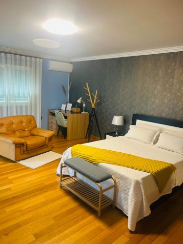 a bedroom with a large bed and a chair at Anjos’home in Viana do Castelo