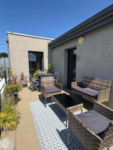 a patio with wicker chairs and tables on a building at ROOF TOP 50m2 VUE MER !! à 2 mn à pied de la PLAGE et de la THALASSOTHERAPIE ! in Concarneau