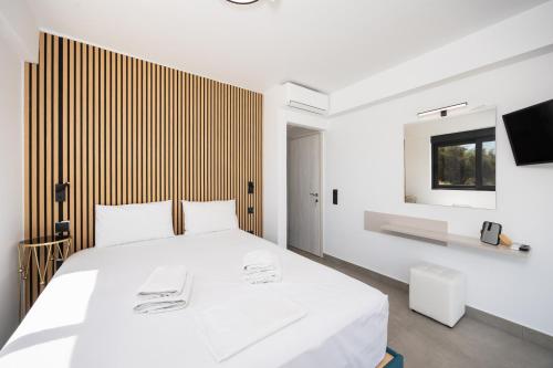 a white bedroom with a white bed and a television at Villa Andria in Apolpaina