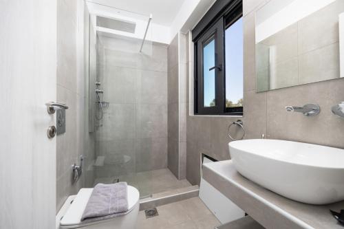 a white bathroom with a sink and a shower at Villa Andria in Apolpaina