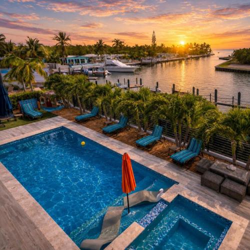 a swimming pool next to a river with a boat at Oceanfront 5BR+ Bonus Room•75’ Dock •Pool-Spa •Kids area •Walk to Sombrero Beach in Marathon