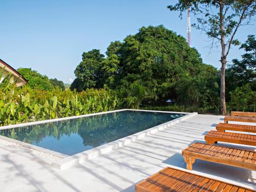 a swimming pool with two wooden benches next to it at Moon Cottage in Choeng Mon Beach